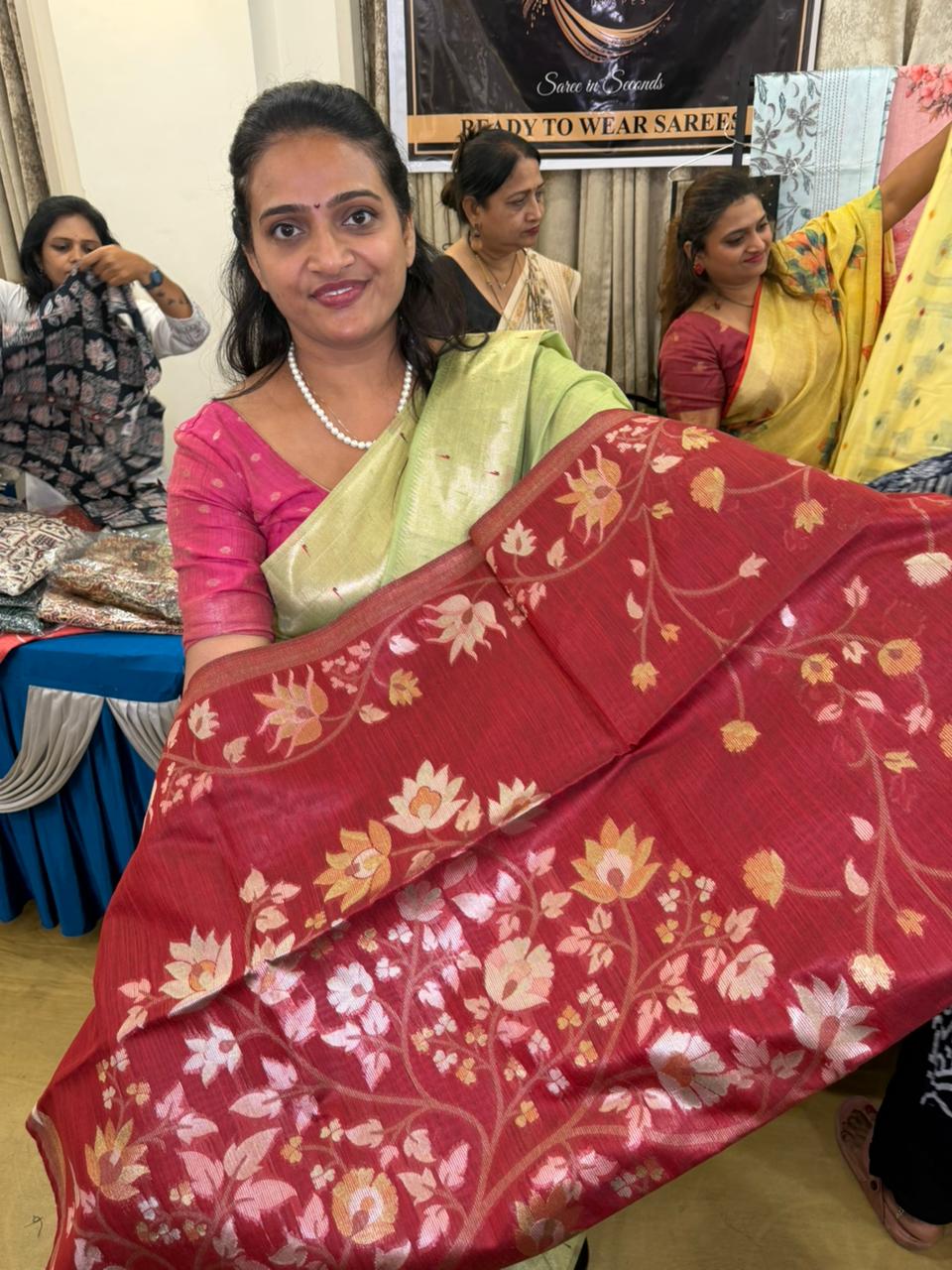 Red floral Banarasi sari held up in the studio